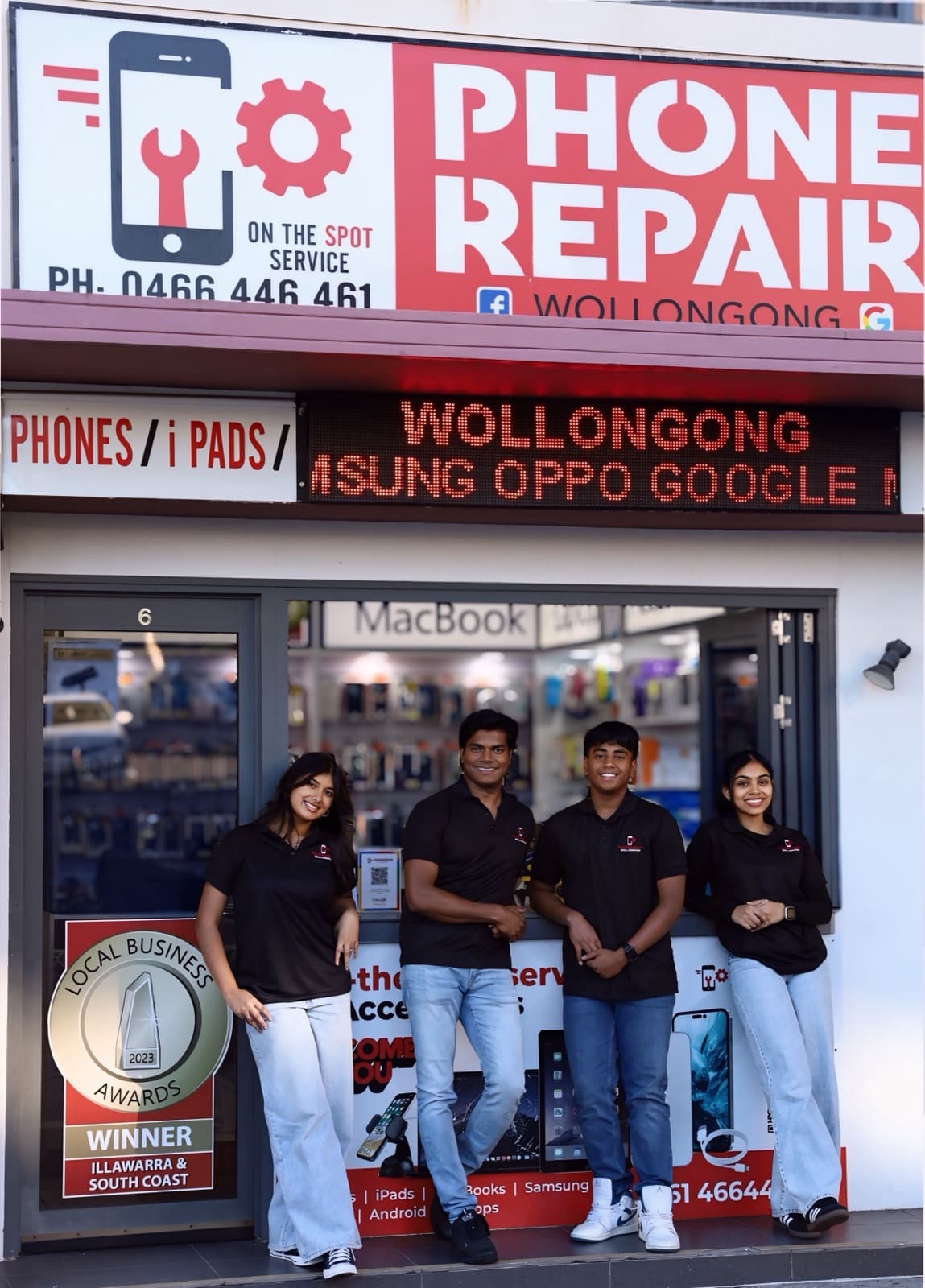 The team standing outside the Phone Repair Wollongong shopfront, below the large red sign, beside the 2023 Illawarra Local Business Awards winner badge.